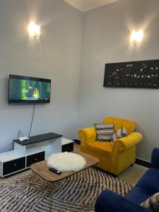 salon z żółtą kanapą i telewizorem w obiekcie Stunning, Romantic and Luxurious Apartment w mieście Dar es Salaam