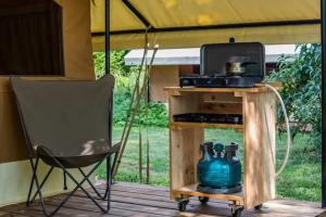 einen Stuhl auf einer Veranda mit einem Tisch und einem Kühlschrank in der Unterkunft Camping Les Peupliers du Lac Onlycamp in Chindrieux