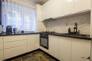 una cocina con armarios blancos y fregadero en MO Apartments Spac, en Brasov