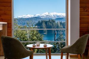 Zimmer mit einem Tisch, 2 Stühlen und einem großen Fenster in der Unterkunft Bahía Montaña Resort in Villa La Angostura