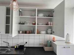 a kitchen with white cabinets with dishes on the shelves at Ferienwohnung *Harz Raum* in Ballenstedt