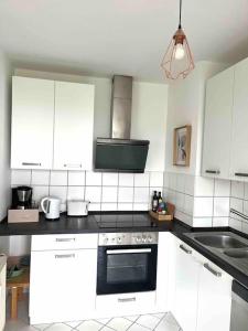 a kitchen with white cabinets and a stove top oven at Ferienwohnung *Harz Raum* in Ballenstedt