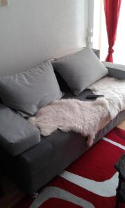 a couch with a white blanket and pillows on it at Bjelasnica Mini Studio in Sarajevo