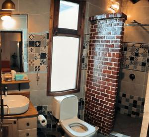 a bathroom with a toilet and a brick wall at Shanti Garden House in Dahab +27 photos