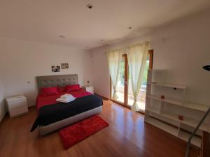 Schlafzimmer mit einem Bett mit roten Kissen und einem Fenster in der Unterkunft AL "Villa Por Do Sol" Sunset Olhão in Olhão