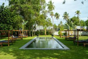 una piscina nel mezzo di un prato con panchine e alberi di Wirdana Resort & Spa a Galle