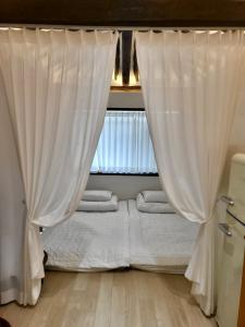 1 cama con cortinas blancas en una habitación con ventana en Hanok Dasi Bom en Gyeongju
