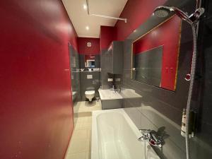 uma casa de banho com paredes vermelhas, uma banheira e um lavatório. em Honigmond Boutique Hotel em Berlim