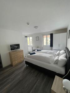 a large white bedroom with a large bed and a tv at Haus zum Rütli in Chur