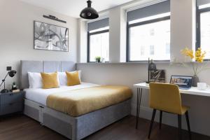 sypialnia z łóżkiem, biurkiem i oknami w obiekcie Vive Hotel w mieście Hastings