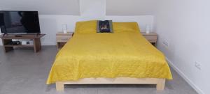 a bed with a yellow comforter and two tables at Atkacs Home in Győr