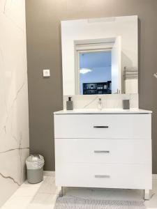 een witte badkamer met een wastafel en een spiegel bij Studio Jungle N2 in Alençon