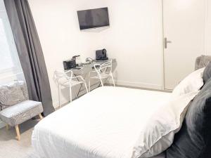 een slaapkamer met een bed, een bureau en een televisie bij Studio Jungle N2 in Alençon