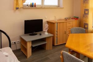 a room with a desk with a television and a table at Ferienwohnung Hirschgrundblick in Oberlungwitz