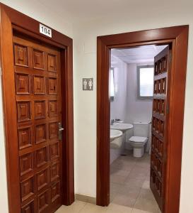 a bathroom with a door and a toilet and a sink at Albergue Zaragoza Camping in Zaragoza