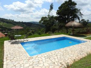 uma piscina com uma mesa e um guarda-sol em chácara Santa luzia em Monte Alegre do Sul