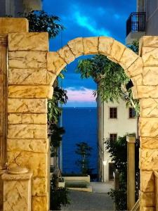 a stone archway with a view of the ocean at Labe Hotel Phú Quốc - Sunset Town - Địa Trung Hải in Phú Quốc