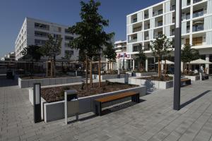 Boardinghotel Westarkaden Suites في هايدلبرغ: حديقة بها مقاعد وأشجار أمام مبنى