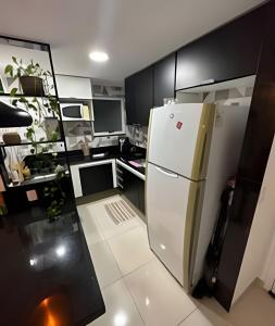 a white refrigerator in a kitchen with black cabinets at aconchegante apt de 1 dormitorio in Rio de Janeiro