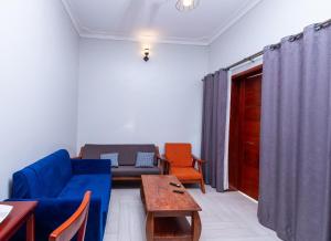 sala de estar con sofá azul y sillas de color naranja en Katente Country Resort, en Kyegegwa