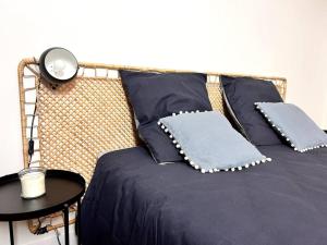 a bed with blue pillows and a table with a lamp at Le P'tit Montreuillois - Appartement proche Paris in Montreuil