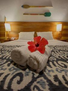 Una cama con una toalla con una flor roja. en Pousada Estrela do Mar Noronha, en Fernando de Noronha
