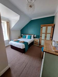 a bedroom with a large bed with blue walls at Hildebrand Guest House in Tenby