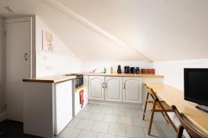 a kitchen with white cabinets and a table with a television at Charmstay Swiss Cottage in London