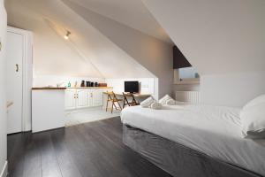 a white bedroom with a bed and a kitchen at Charmstay Swiss Cottage in London