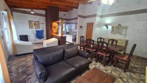 a living room with a leather couch and a dining room at Sonidos del Mar in Balneario El Condor