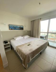 a bedroom with a large bed and a large window at Macaé Ramada Flat RJ in Macaé