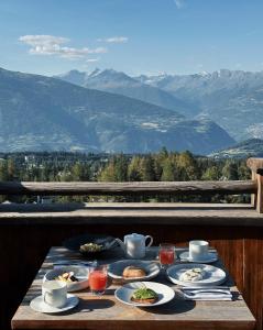 una mesa con comida y vistas a las montañas en LeCrans, en Crans-Montana