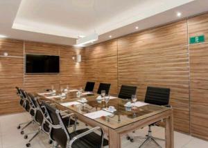 uma sala de conferências com uma mesa longa e cadeiras em Macaé Ramada Flat RJ em Macaé