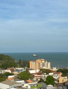 vistas a una ciudad con un barco en el océano en Macaé Ramada Flat RJ en Macaé