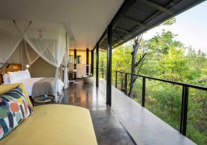 a bedroom with a bed and a balcony at The Outpost & Pel's Post in Makuleke Contract Park