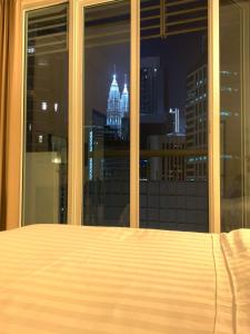 a bed in a bedroom with a view of the city at Sweet Home By Seri Bukit Ceylon Residency in Kuala Lumpur