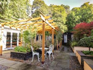 a patio with a table and chairs under a wooden pergola at The Secret Garden at Old Drynie House in Inverness