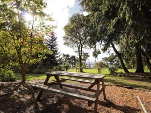 drewniana ławka piknikowa w parku z drzewami w obiekcie The Secret Garden at Old Drynie House w mieście Inverness