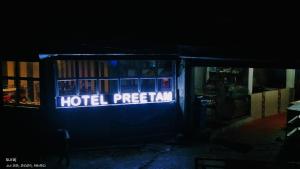 una señal de registro del hotel en un edificio por la noche en Hotel Preetam Uttarakhand, en Lokpāl