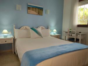 a bedroom with a large white bed with a blue blanket at Hostal Los Pinares in Lloret de Mar