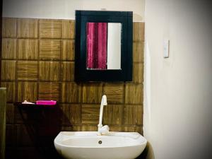 y baño con lavabo blanco y espejo. en Residence Inn, en Angunakolapelessa