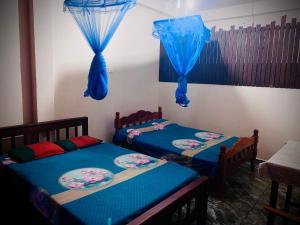 2 Einzelbetten in einem Zimmer mit blauen Vorhängen in der Unterkunft Residence Inn in Angunakolapelessa