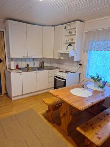 a kitchen with white cabinets and a wooden table at Esterin Tupa, Alajärvi 