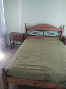 sypialnia z łóżkiem z drewnianą ramą i stołem w obiekcie Casa Rosa w mieście Balneario Claromecó