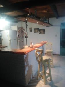 a kitchen with a bar with two chairs and a refrigerator at Casa Rosa in Balneario Claromecó