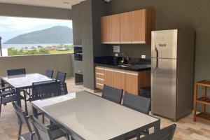 uma cozinha e sala de jantar com mesas e um frigorífico em Lindo apartamento Ubatuba em Ubatuba