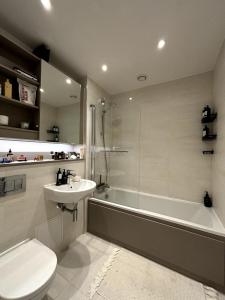 a bathroom with a sink and a tub and a toilet at Stylish 2BD Flat wIncredible View of London - Bow in London