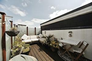 balcón con sofá, mesa y sillas en Chic 3BD Maisonette wRoof Terrace - Wandsworth!, en Londres