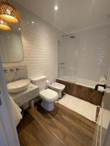 a bathroom with a toilet and a sink and a tub at El Salto Suites - Casonas del Haras in Mar del Plata
