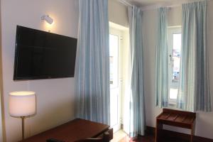 um quarto de hotel com uma televisão de ecrã plano na parede em Hotel Santo Antonio Da Baia em São Martinho do Porto